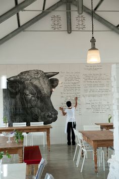 a man standing in front of a large cow head on the side of a wall