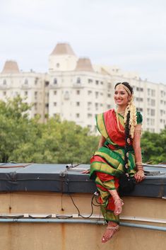 a woman sitting on top of a roof with buildings in the backgrouds