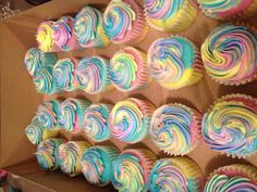 a box filled with cupcakes covered in multi colored frosted swirled icing