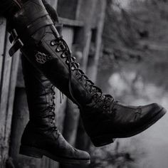 black and white photograph of woman's legs wearing boots with laces on them