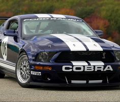 a blue mustang with white stripes parked in a parking lot