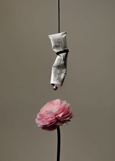 a pink flower is hanging upside down on a black pole with two packets attached to it