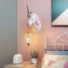 a bed with a pink wall and a white unicorn head lamp on top of it