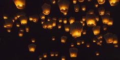 many lit up lanterns floating in the air