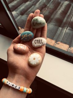 someone is holding up some rocks with words painted on them to spell out their name