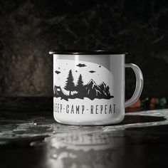 a white and black camp mug sitting on top of a table