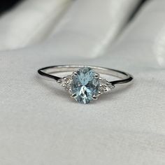 a blue diamond ring sitting on top of a white cloth