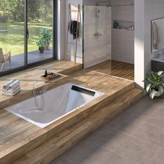 a bath tub sitting on top of a wooden counter next to a shower and window