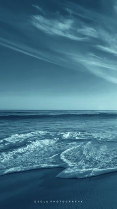 an ocean beach with waves coming in to shore and blue sky filled with white clouds