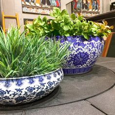 two blue and white planters sitting on top of a table