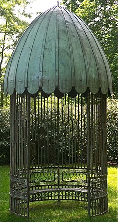 a metal birdcage sitting on top of a lush green grass covered park area