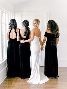 three women in black and white dresses looking at each other's back while they are standing near a window