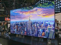 people are standing in front of a large television screen with the city skyline on it