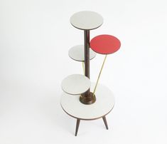 a three tiered table with red and white plates on it's top, in front of a white background