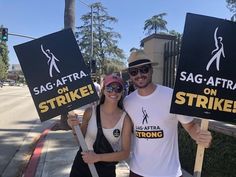 a man and woman holding up signs on the side of the road that read sag - aftra strike on strike