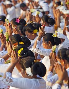 many women in white dresses are clapping and holding their hands up with yellow flowers on them