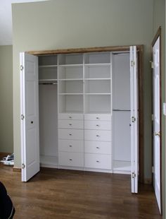 an empty room with white closets and drawers in the center, on hard wood flooring