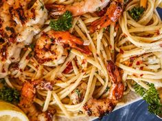 pasta with shrimp, parsley and lemon wedges on a plate