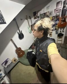 a person holding a guitar in a room with guitars on the wall