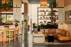 a living room filled with furniture next to a kitchen and dining room table covered in potted plants