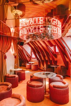 the interior of a fancy bar with red velvet seating and chandelier hanging from the ceiling