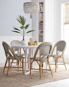 a white table with four chairs and a potted plant