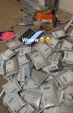 a pile of silver packets sitting on top of a floor next to a laptop computer