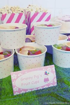 there are many cups that have fruit in them on the table with pink and white striped bags