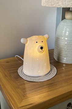 a white bear lamp sitting on top of a wooden table next to a lamp shade