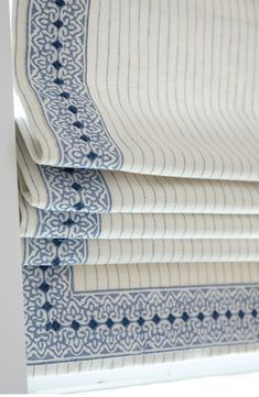 roman blinds with blue and white designs on them in a window sill, close up