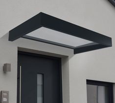 a black door and some windows on a white building with a skylight above it