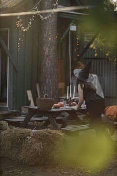 a woman dressed as a witch sitting at a picnic table