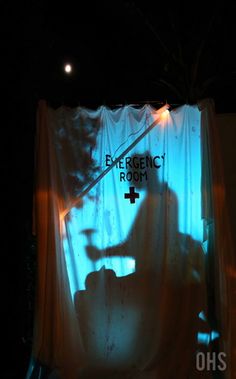 the silhouette of a person sitting on a chair in front of a curtain with an emergency sign projected on it