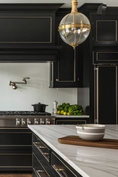 a kitchen with black cabinets and white counter tops, an island in the middle has a bowl on it