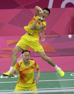 two tennis players jumping up to hit the ball with their rackets in front of them