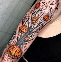 a woman's arm with pumpkins and bats on it, all around the tree