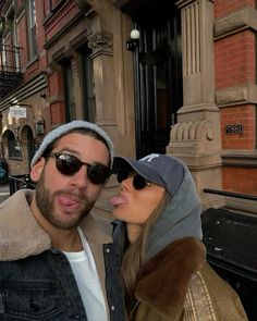 a man and woman standing next to each other in front of an old brick building