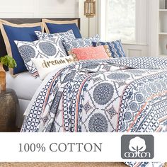 a bed covered in blue and white comforter next to a window with the words cotton on it