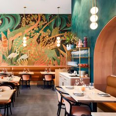 the interior of a restaurant with tables, chairs and artwork on the wall behind them