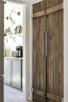 an open wooden door in a kitchen next to a refrigerator