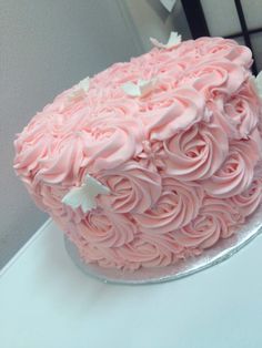 a pink frosted cake sitting on top of a table