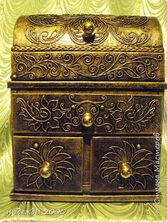 an ornately decorated metal box with two drawers on the front and one door open