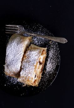 powdered pastry on a black plate with a fork