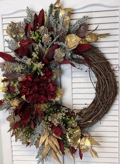 a wreath with red flowers and gold leaves is hanging on the front door to welcome guests