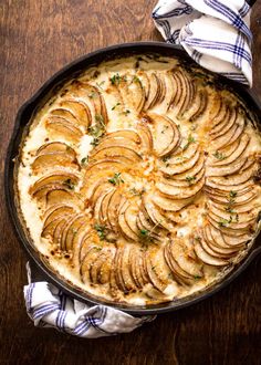 baked potato dish in a cast iron skillet on top of a wooden table with blue and white napkins