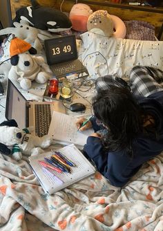 a person laying on a bed with stuffed animals and laptops in front of them