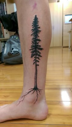 a person with a tattoo on their leg that has a tree growing out of it