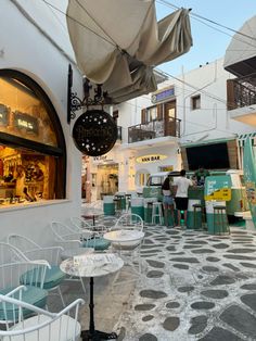 an outdoor cafe with tables, chairs and umbrellas