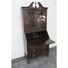 an antique desk with glass doors and drawers