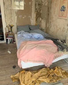 an unmade bed sitting on top of a wooden floor